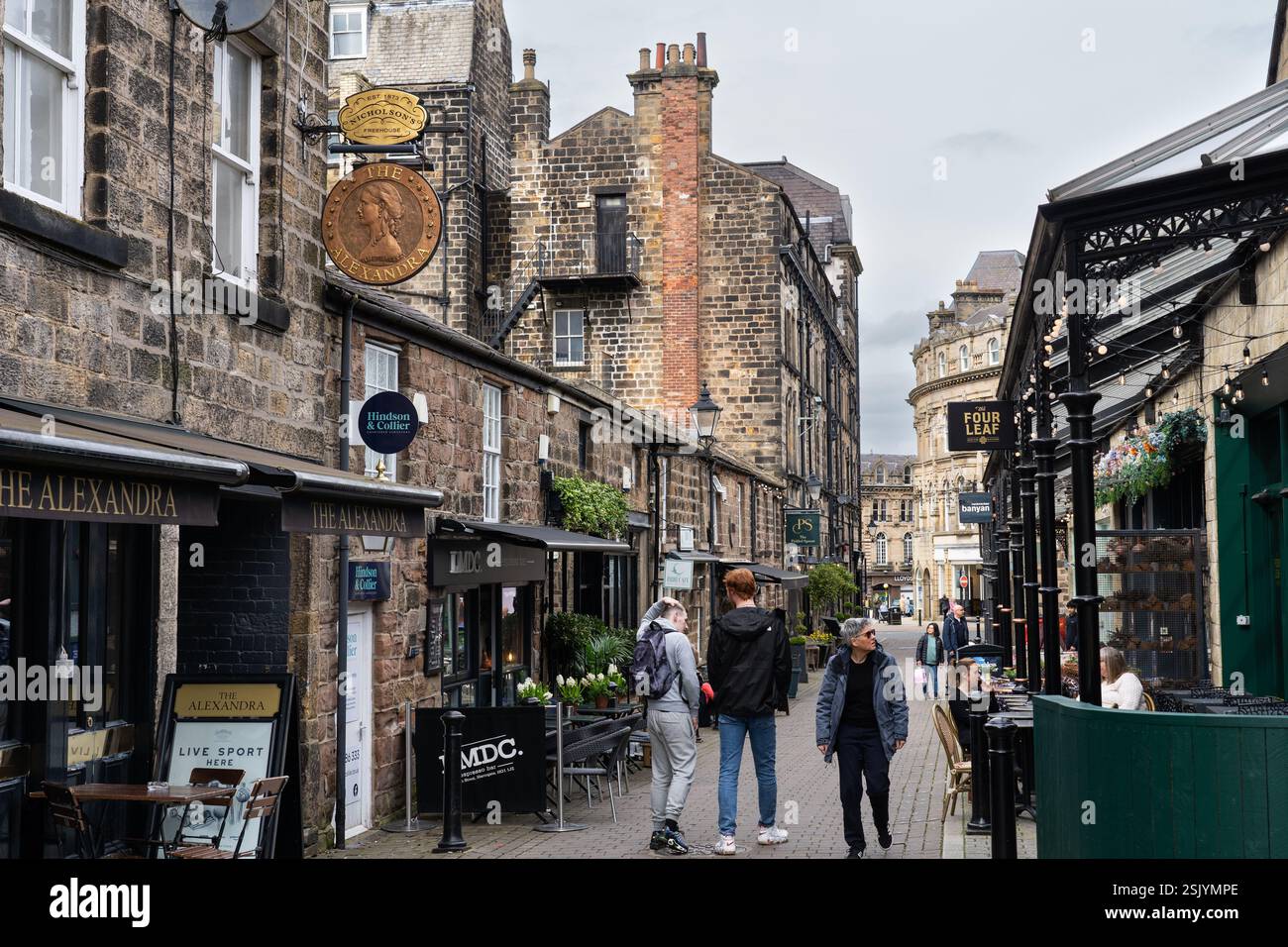 Menschen gehen an traditionellen Sandsteingebäuden vorbei, Cafés, Bars und Restaurants in der John Street in der Altstadt von Harrogate, England Stockfoto