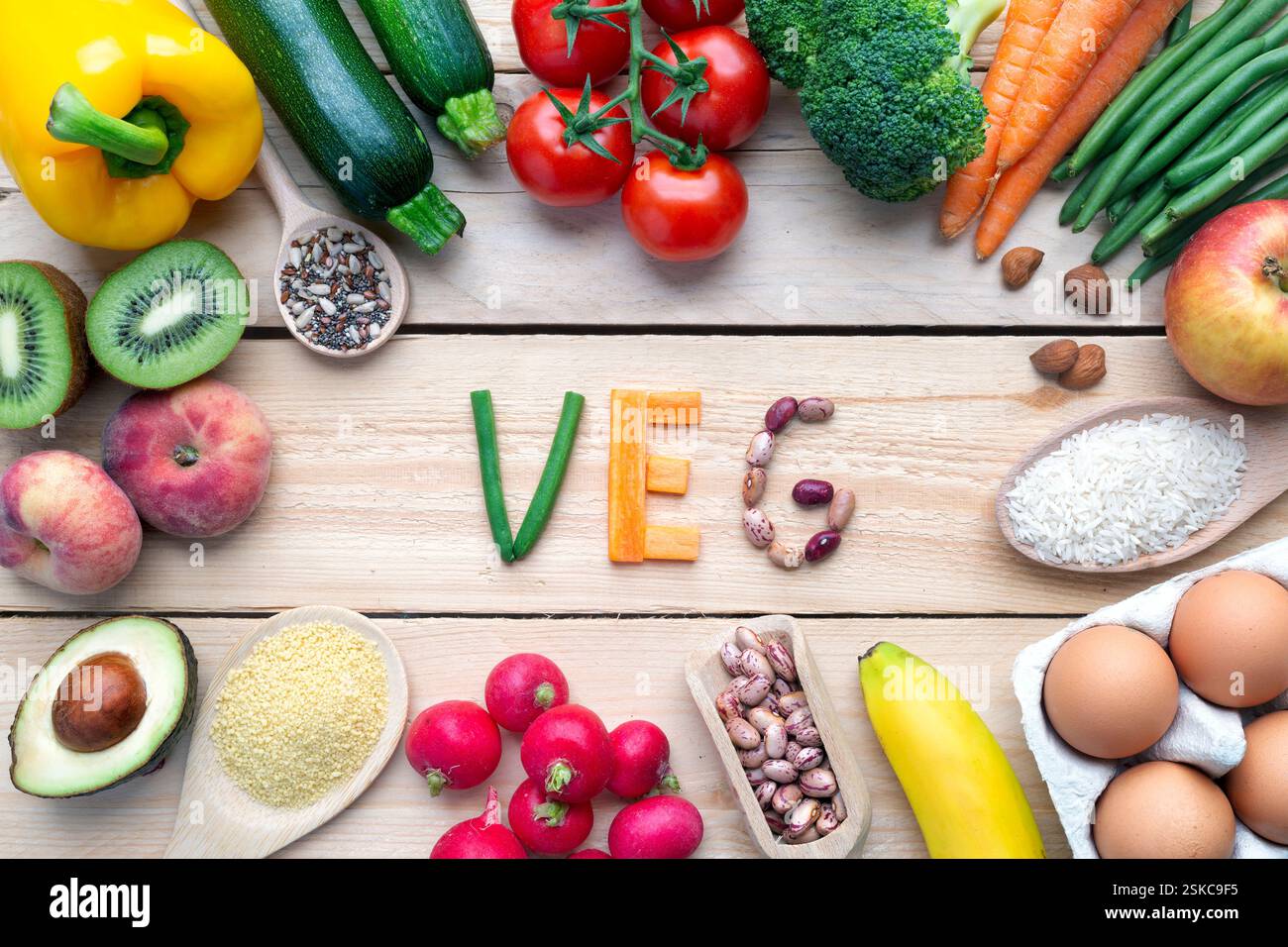 Gesundes veganes Mittagessen mit Avocado, Uova, Verdura, Frutta, Riso, halb auf Holzhintergrund. Draufsichten. Stockfoto
