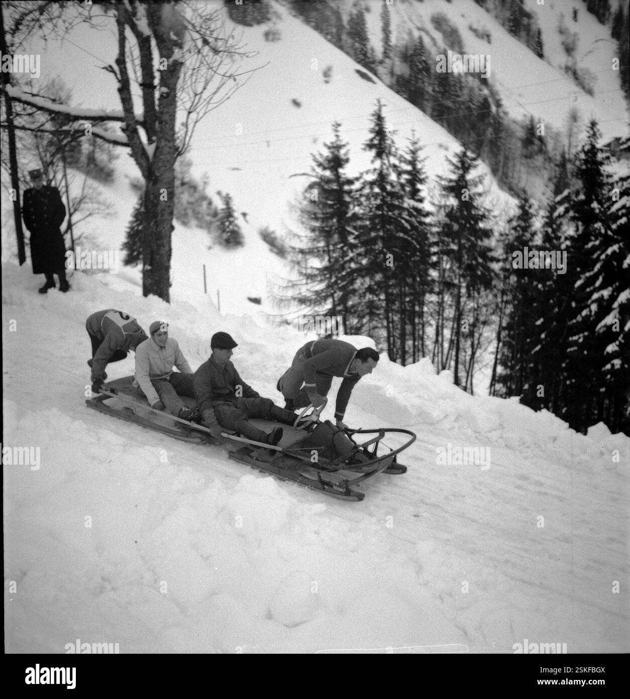 Kurz nach dem Start; da die Bahn stark verschneit war, müssen die Konkurrenten auf der offenen Strecke durch stossen den Bob wieder in Fahrt bringen#kurz nach dem Start; da die Bahn stark verschneit war, mussten die Teilnehmer während des Rennens den Bob schieben----- Schweizer Bob-Meisterschaft, Les Avants 1951: Chenaux (Les Avants)#Swiss Bobsleigh Championship, Les Avants 1951: Chenaux (Les Avants)- RDB VON DUKAS Stockfoto