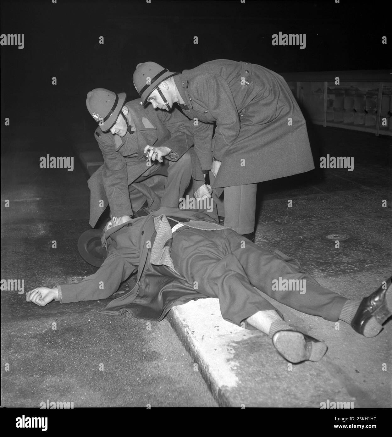 Polizisten kümmern sich um einen Mann der auf der Straße liegt;Verletzter Mann-- Stadtpolizei Zürich 1946#Metropolitan Police, Zürich 1946- RDB VON DUKAS Stockfoto