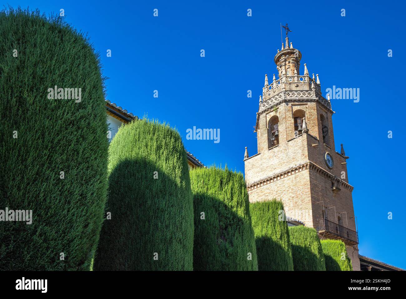 Ronda Stadt in Spanien. Historischer Glockenturm und gepflegte Hecken unter einem leuchtend blauen Himmel. Stockfoto