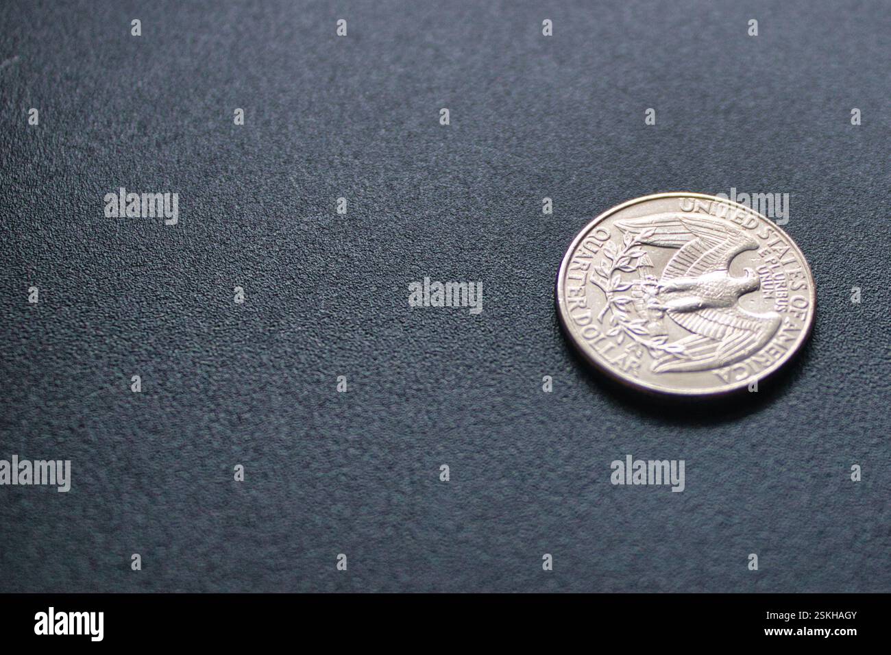 Nahaufnahme einer Vierteldollar-Münze mit komplizierten Details auf einem strukturierten Hintergrund, die amerikanische Währung und wirtschaftliche Konzepte repräsentieren Stockfoto