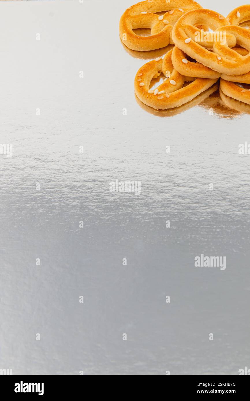 Frisch gebackene weiche Brezeln sind ordentlich auf einer reflektierenden Oberfläche angeordnet. Ihre goldbraune Farbe und das Salz machen sie zu einem einladenden Imbiss für einen Stockfoto