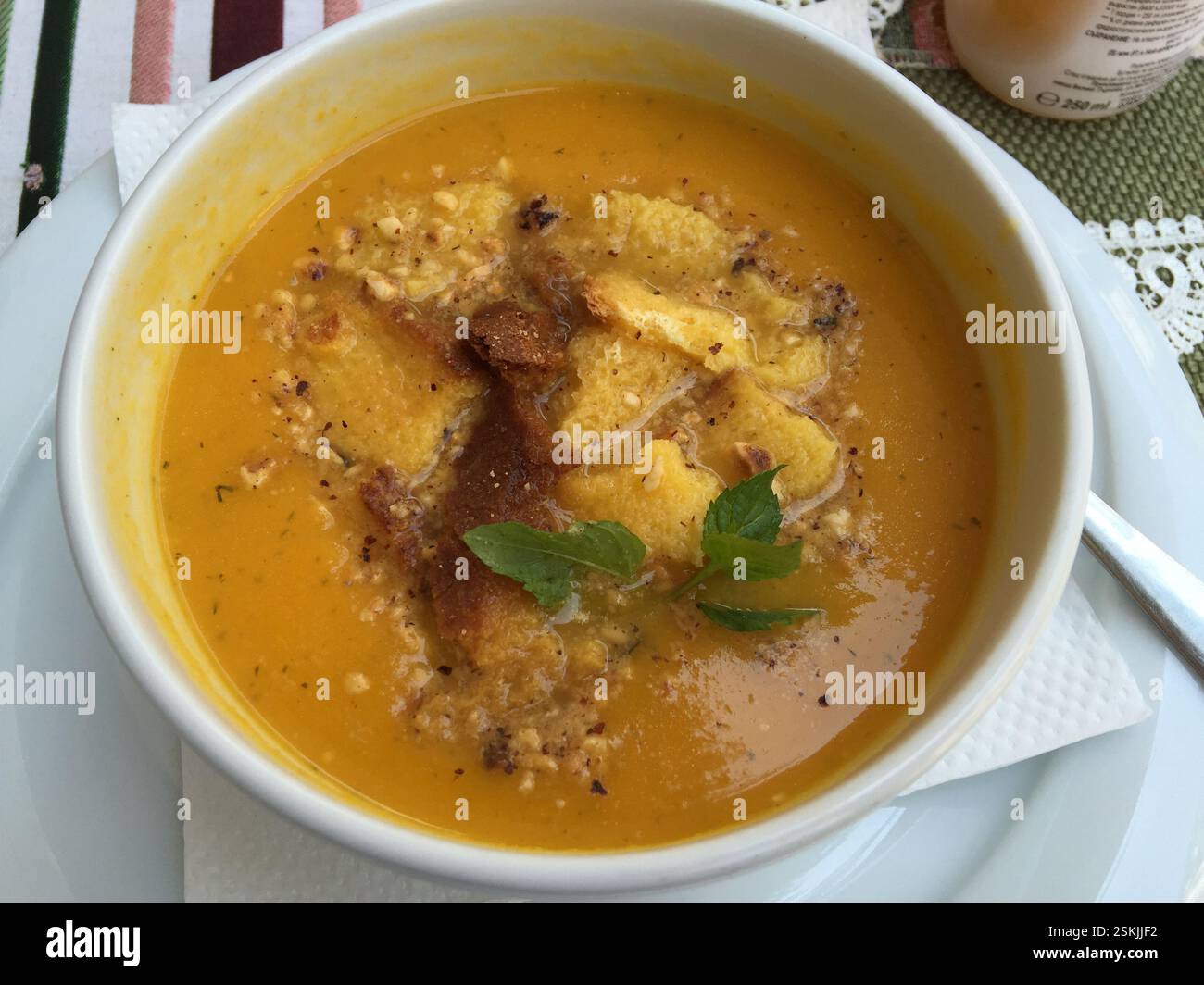 Eine herzhafte Schüssel mit traditioneller bulgarischer Suppe steht dampfend auf einem rustikalen Holztisch, umgeben von frisch gebackenem Brot. Bulgarien. Die Suppe, bekannt als die Stockfoto