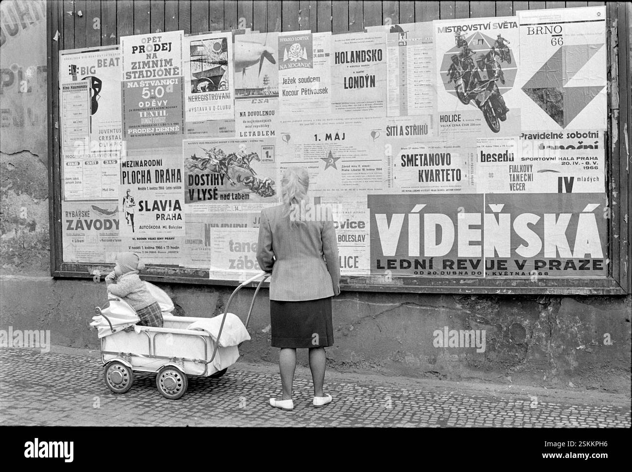 --- Frau mit Kinderwagen beim Lesen eines 1.Mai-Plakats, Prag 1966#Frau mit Kinderwagenlesung 1. Mai Poster, Prag 1966- RDB VON DUKAS Stockfoto