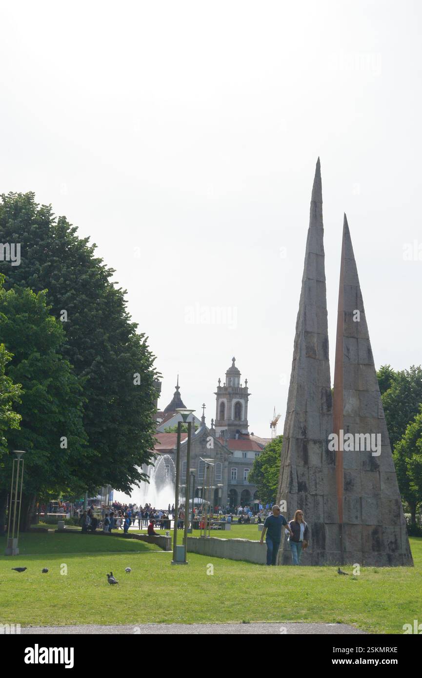 Der imposante Obelisk dominiert den Park in Braga, Portugal. Kirche und Brunnen schaffen eine ruhige Kulisse. Symbol des Glaubens und der Hoffnung in einer ruhigen urbanen Oase. Stockfoto