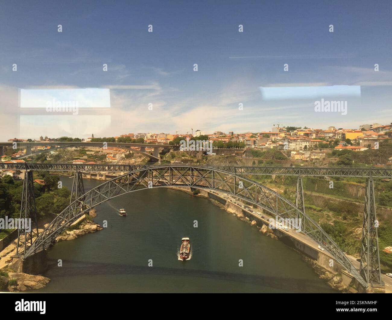 Braga, Portugal. Ein faszinierendes Stadtbild entfaltet sich, zwei Brücken, die sich anmutig über einen pulsierenden Fluss bogen. Üppiges Grün umgibt die Ufer, während Boote tanzen Stockfoto