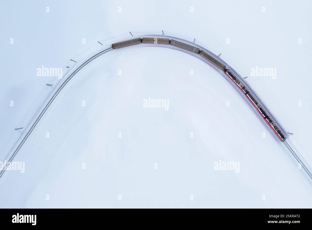 Blick aus der Vogelperspektive auf den berühmten Bernina Express, der im Winter am Bernina Pass vorbeifährt. Graubünden, Engadin, Schweiz. Stockfoto