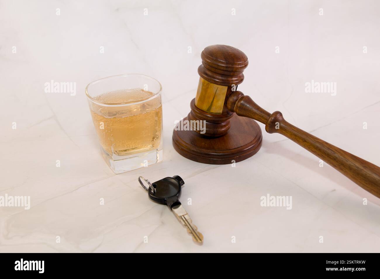 Der legale Hammer neben einem Getränk und Autoschlüsseln steht für die Gefahren des Trinkens und Fahrens vor Gericht. Stockfoto