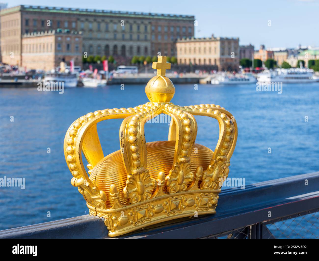 Eine vergoldete Krone in der Mitte der Skeppsholm-Brücke in Stockholm, Schweden, mit dem Königspalast im Hintergrund. Stockfoto