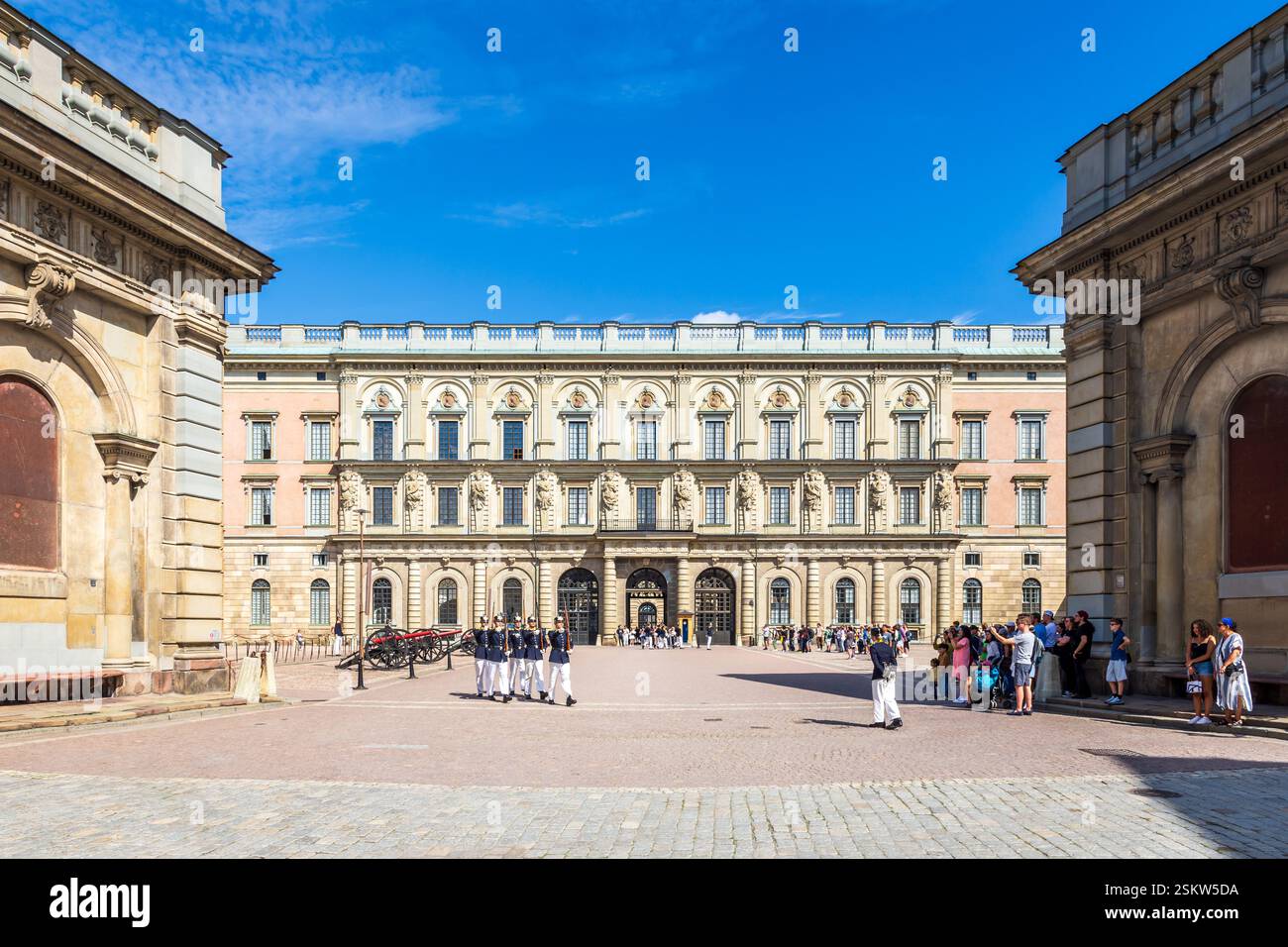 Eine kleine Gruppe von Kaisergarden verlässt den äußeren Innenhof des Königspalastes in Stockholm, Schweden, und geht Schritt unter den Augen der Touristen. Stockfoto