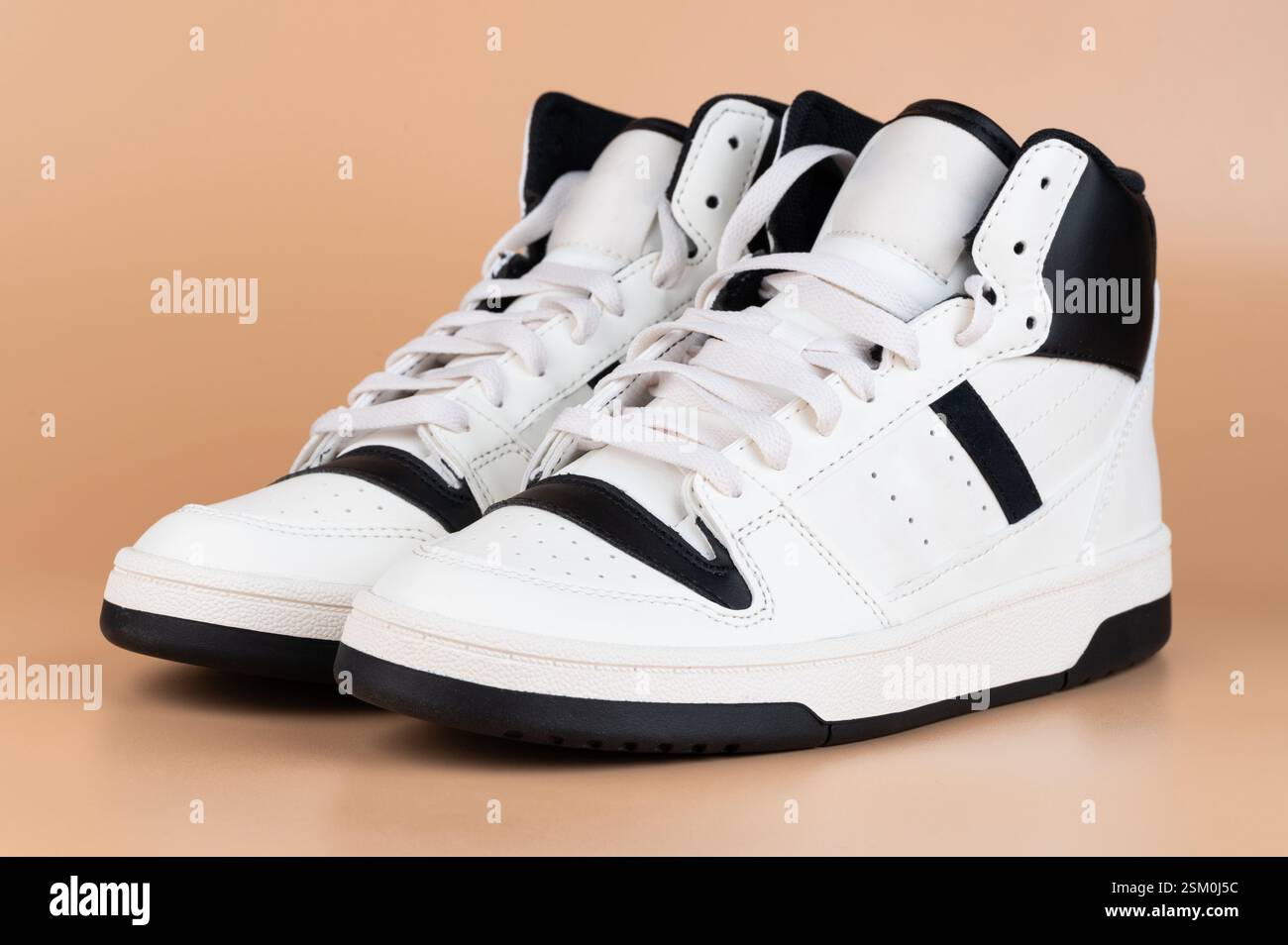 Die High-Top-Sneakers sind aus weißem Leder mit schwarzen Akzenten gefertigt und eignen sich perfekt für Freizeitkleidung und stylische Outfits. Stockfoto