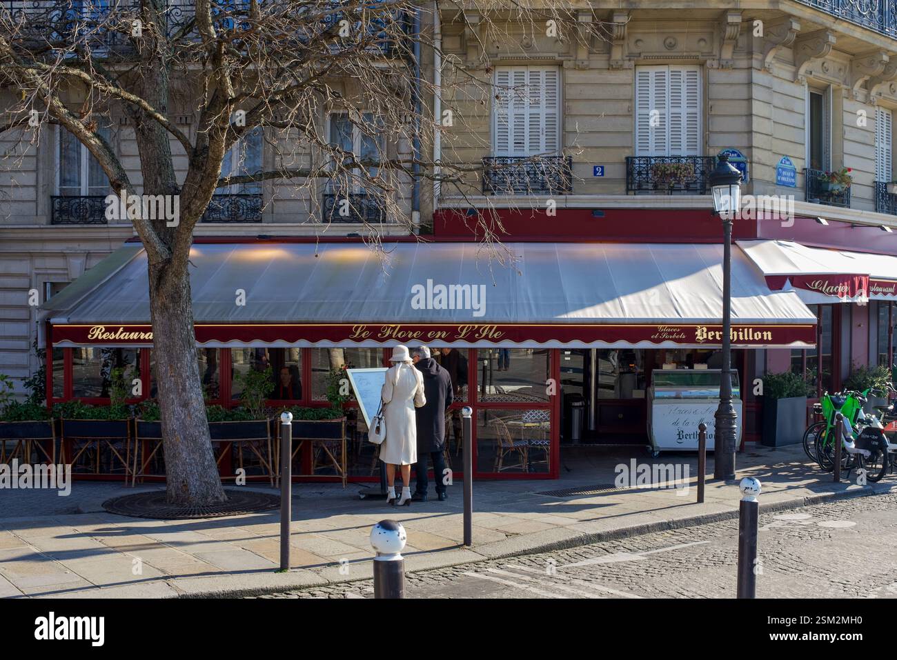Ein elegantes Paar, das sich vor einem Restaurant im 4. Arrondissement von Paris ein Menü anschaut Stockfoto