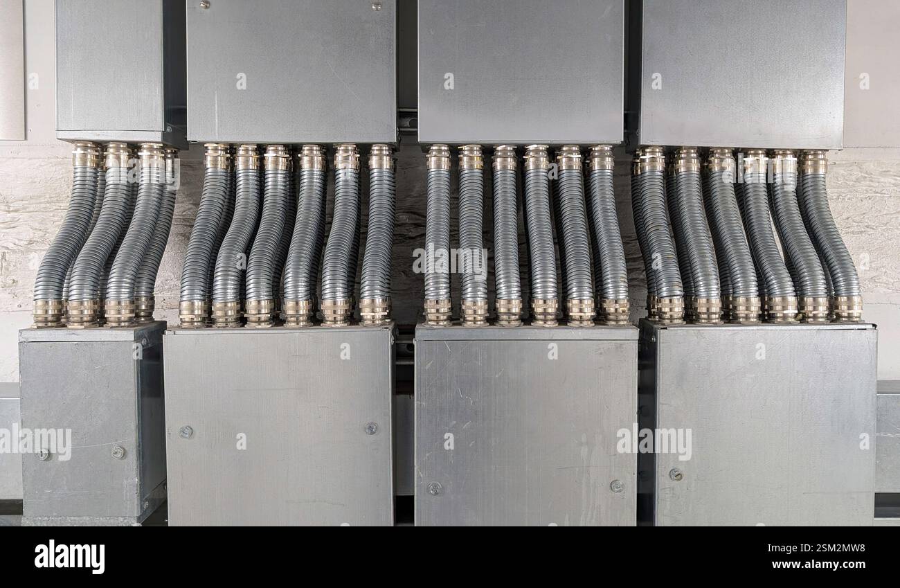 Symmetrische Anordnung flexibler metallischer Kabelkanäle (FMC), die an große elektrische Anschlusskästen angeschlossen sind. Stockfoto