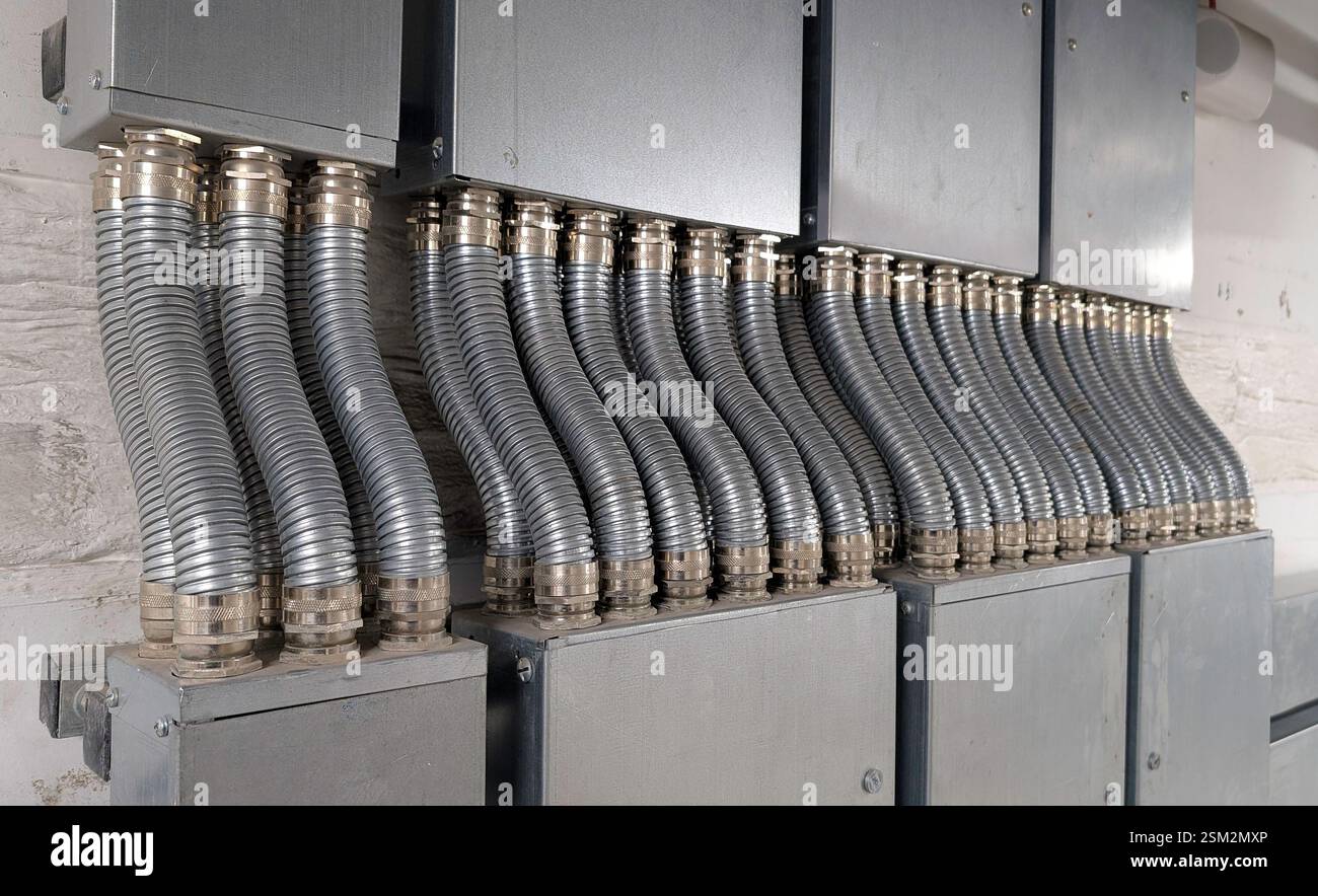 Symmetrische Anordnung flexibler metallischer Kabelkanäle (FMC), die an große elektrische Anschlusskästen angeschlossen sind. Stockfoto
