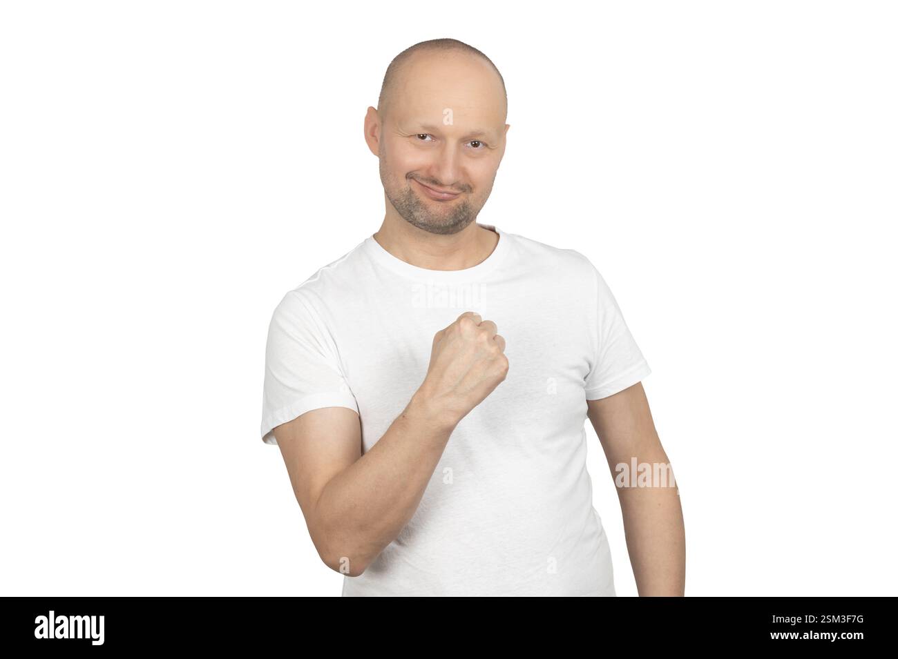 Ein kahler Mann in einem weißen T-Shirt drückt selbstbewusst seine Faust und drückt Stärke und Entschlossenheit aus. Stockfoto Ein kahler Mann in einem weißen T-Shirt drückt selbstbewusst seine Faust und drückt Stärke und Entschlossenheit aus. Stockfoto