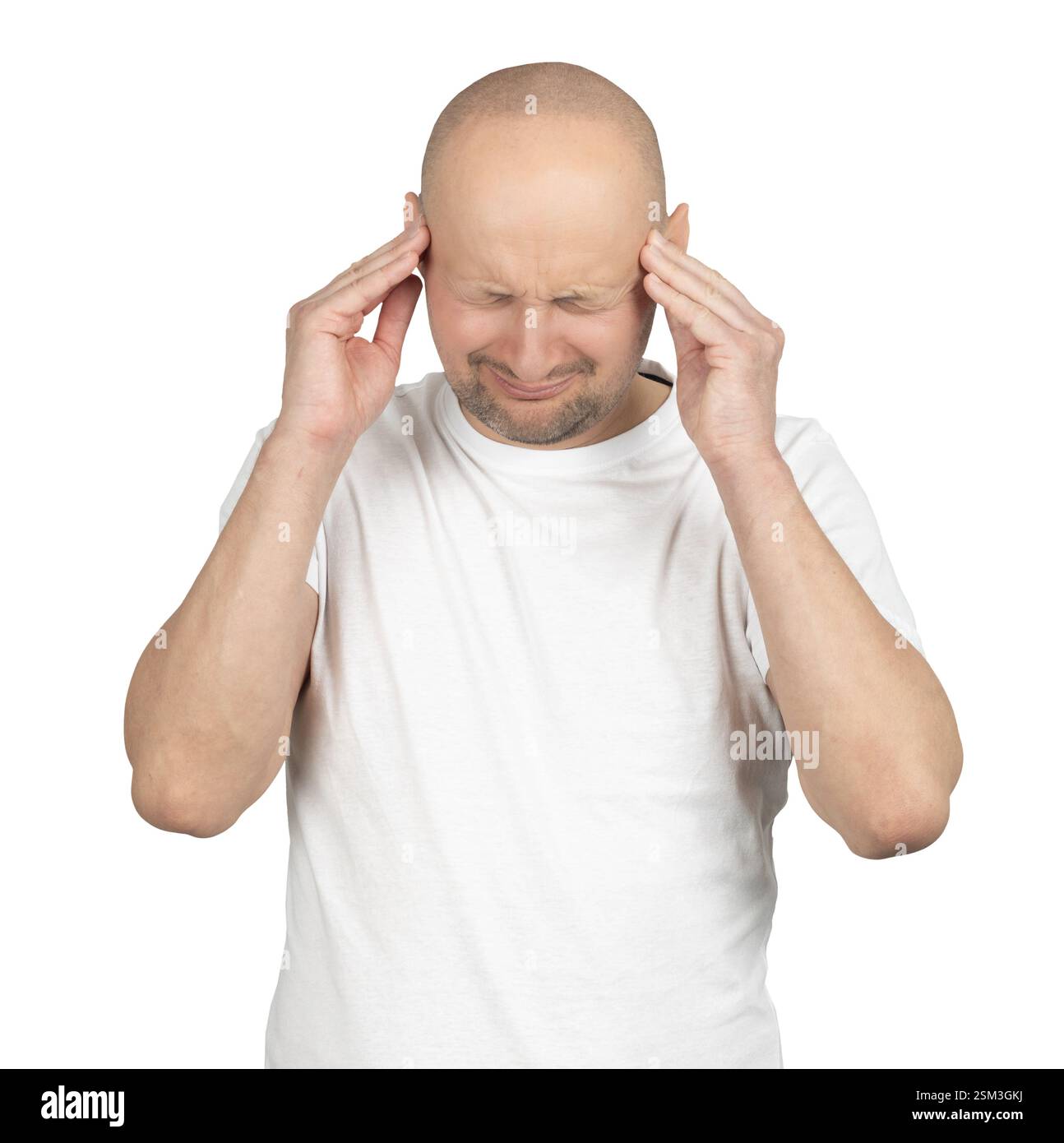 Ein kahler Weißer in einem weißen T-Shirt steht vor einem neutralen Hintergrund. Er drückt seine Schläfe mit beiden Händen und zuckt sichtbare Schmerzen zu. Stockfoto