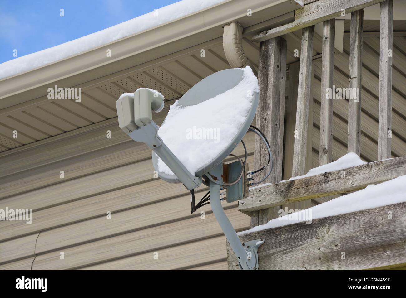 Schnee sammelt sich auf einer Satellitenschüssel nach einem Winterschneesturm, der den TV- und Internetdienst stört. Stockfoto