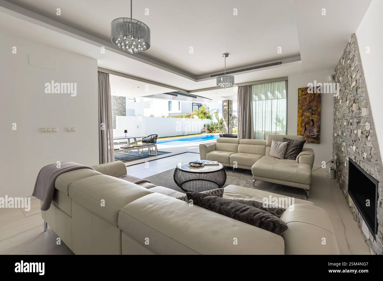 Ein Bild mit Blick auf den privaten Swimmingpool vom luxuriösen Wohnzimmer in einem mediterranen Ferienhaus Stockfoto