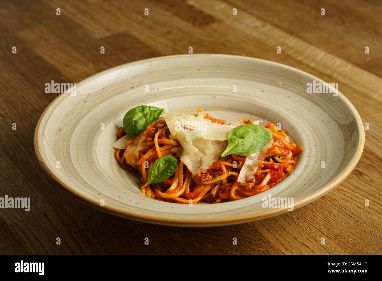 Eine wunderschön überzogene Portion Spaghetti mit reichhaltiger Tomatensauce, garniert mit frischen Basilikumblättern und geriebenem Parmesankäse. Das Gericht ist ser Stockfoto
