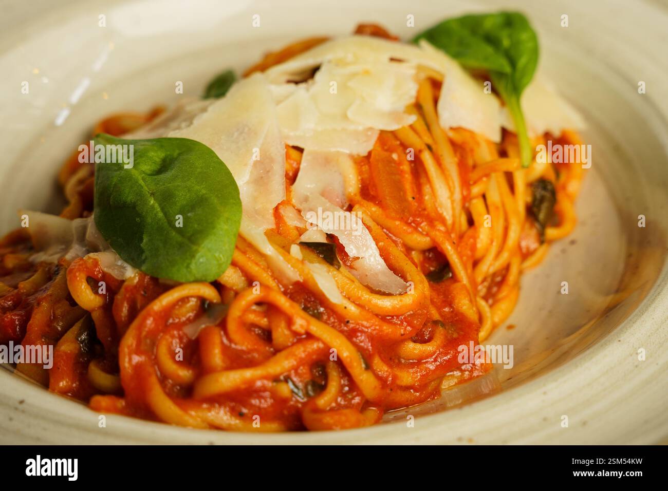 Eine wunderschön überzogene Portion Spaghetti mit reichhaltiger Tomatensauce, garniert mit frischen Basilikumblättern und geriebenem Parmesankäse. Das Gericht ist ser Stockfoto