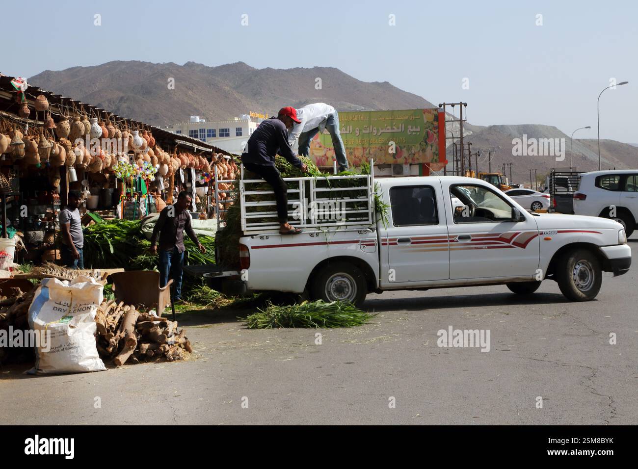 Männer, die Tierfutter vom Pick-up-Truck im Souq Fanja Al-Hadith Oman abladen Stockfoto