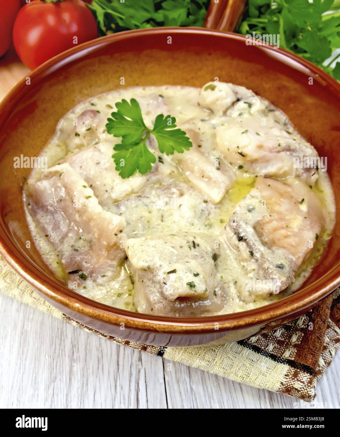 Fisch-Eintopf in Sahne-Sauce in einem keramischen Pfanne, Petersilie, Serviette auf den Hintergrund Licht Holzbrettern Stockfoto