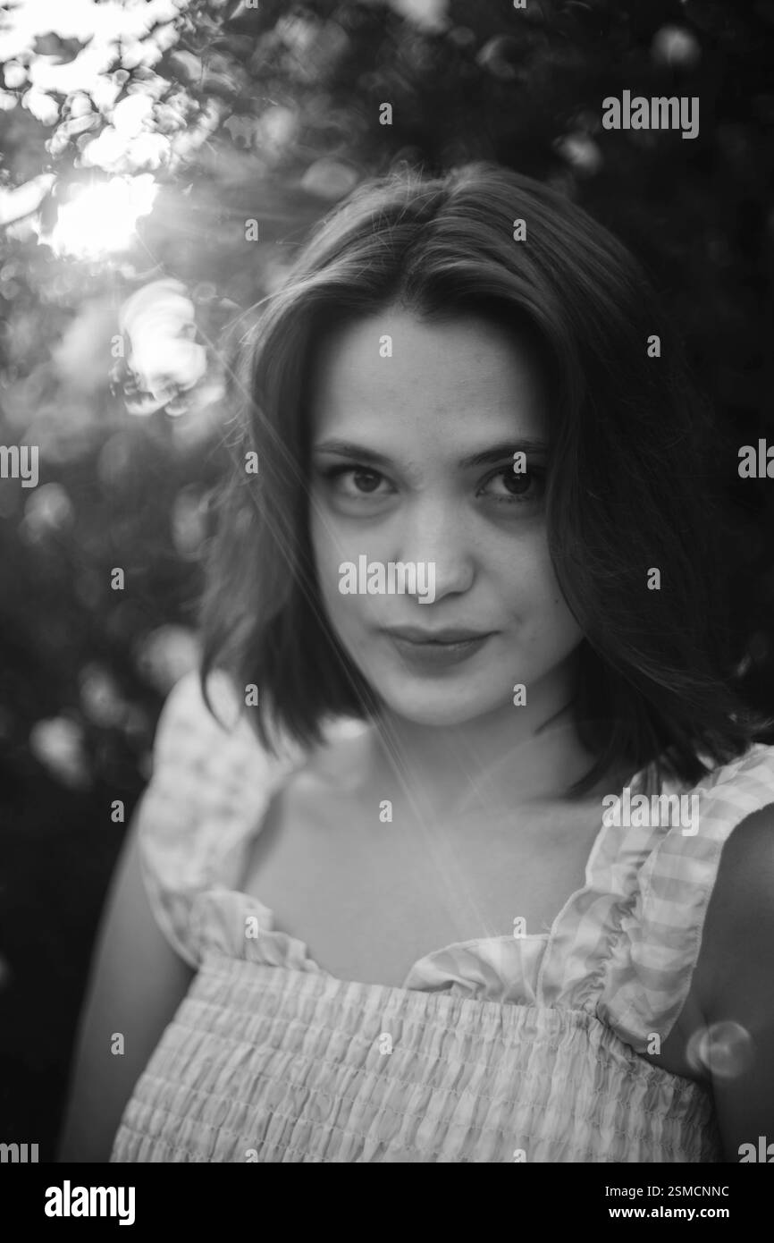 Nahaufnahme eines schwarz-weißen Portraits einer Frau mit Sonnenlicht und Blumen Stockfoto