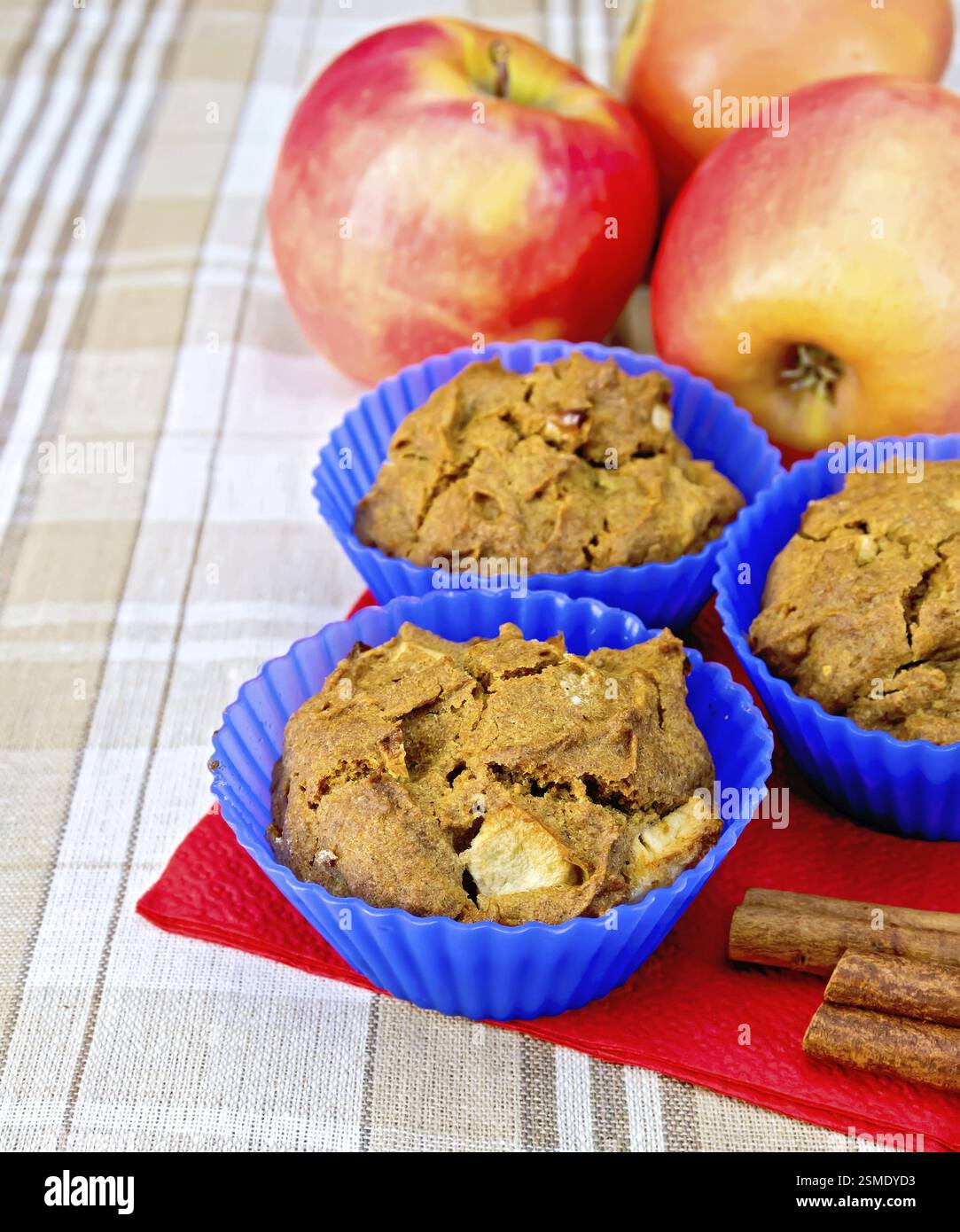 Cupcakes Roggen mit Apfel in Silikonformen auf roter Papierserviette, Äpfel und Zimt auf einem Hintergrund einer Leinentischdecke Stockfoto