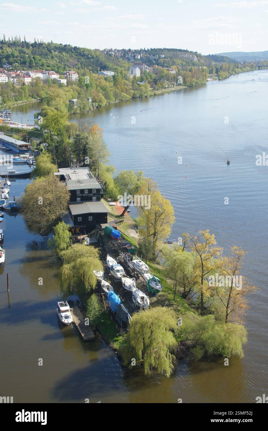 Aus der Vogelperspektive auf die Moldau in Prag, mit der Burg Vyšehrad auf dem Hügel im Hintergrund. Boote legten an der Küste an, mit üppigem Grün rund um t Stockfoto