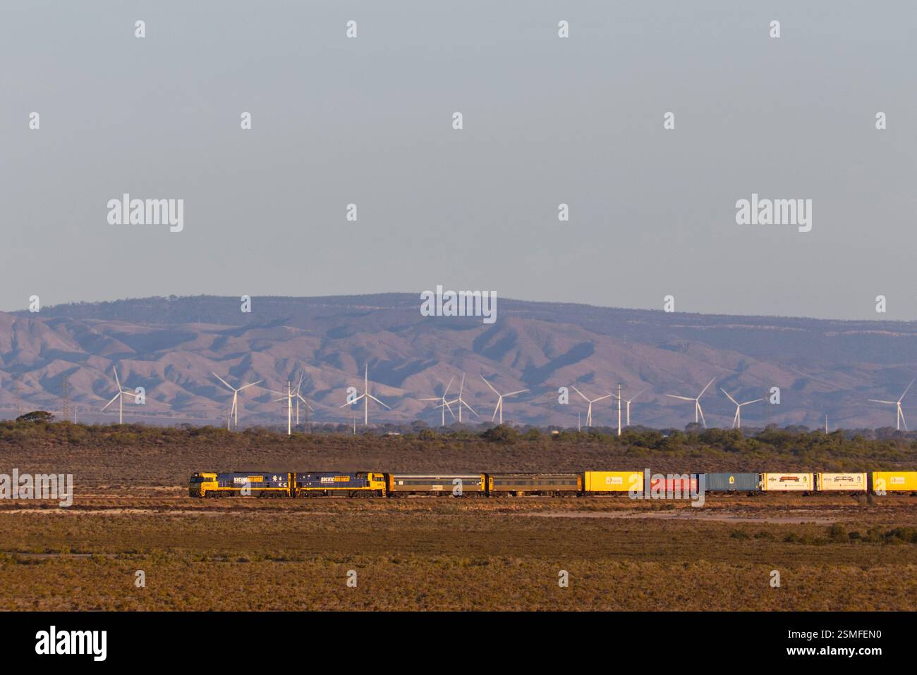 Container-Güterzug, der vor den Flinders Ranges und den Wind Turbines des Port Augusta Renewable Park South Australia vorbeifährt Stockfoto