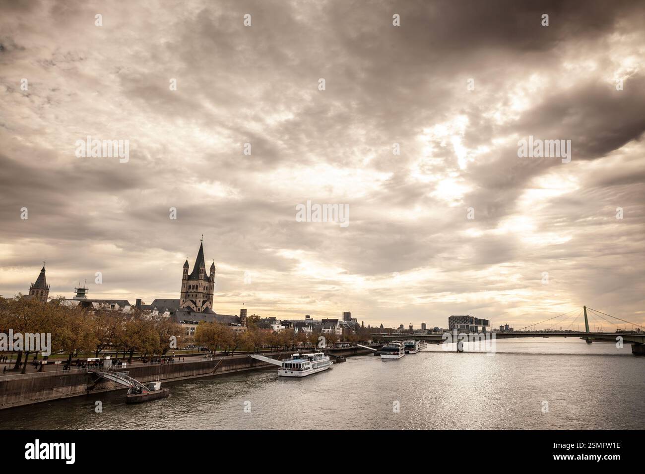 Trankgassenwerft-Promenade am rhein in Köln, Köln, Deutschland, mit Kreuzfahrtschiffen, die in der Abenddämmerung auf Touristen warten. Die Kirche von Gross Stockfoto