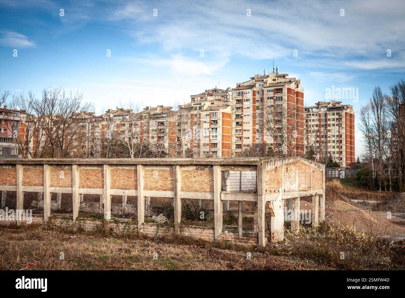 Ein verlassenes Industriebauwerk steht vor hoch aufragenden Wohnblöcken aus der kommunistischen Ära. In Pancevo, serbien, zeigt diese schroffe Szene den Bankrott, sh Stockfoto