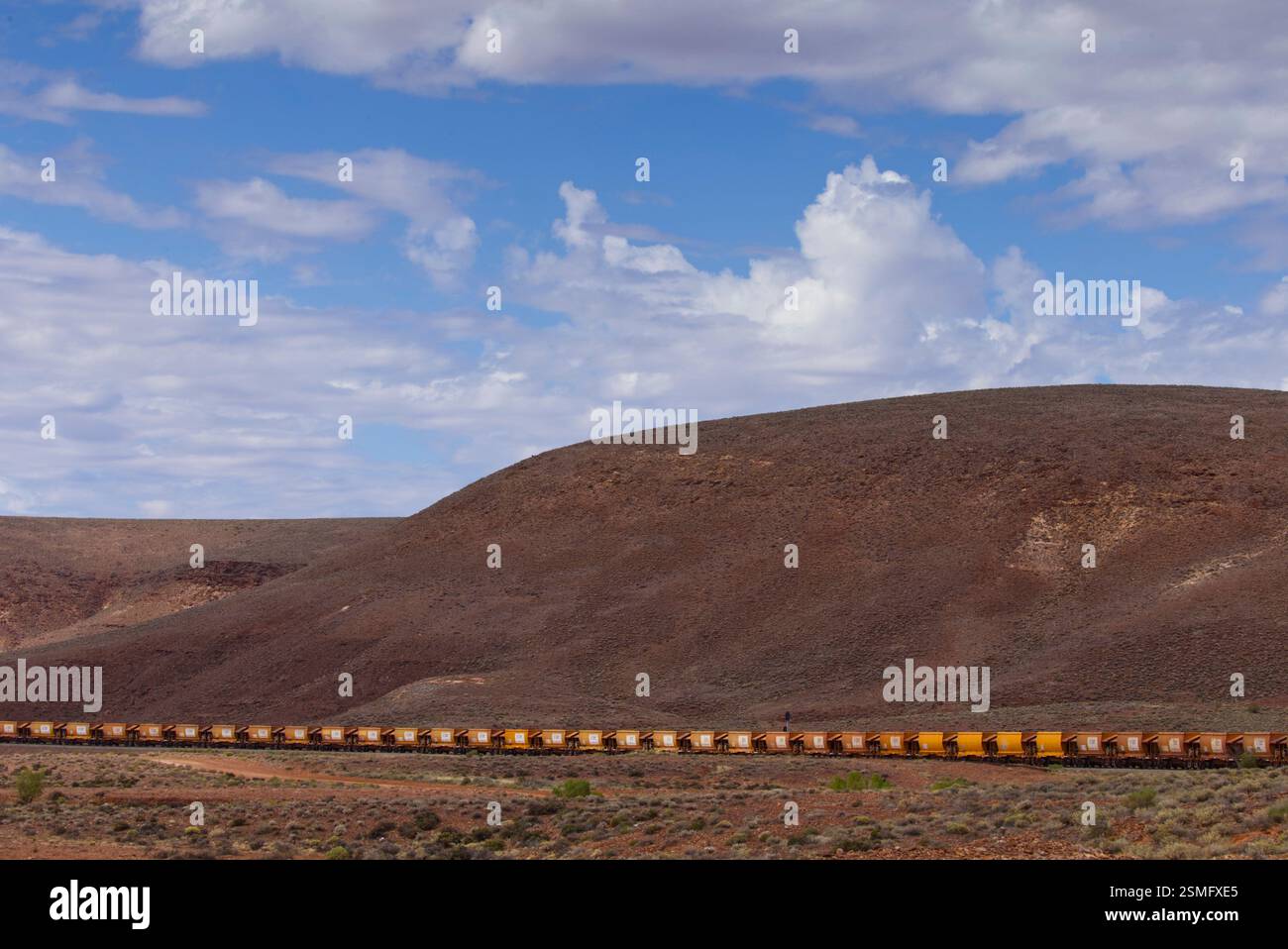 Der Eisenerzzug Aurizon, der aus mehreren Wagen besteht, wird in Bewegung auf einer Strecke erfasst, die sich durch die Landschaft zieht. Stockfoto Der Eisenerzzug Aurizon, der aus mehreren Wagen besteht, wird in Bewegung auf einer Strecke erfasst, die sich durch die Landschaft zieht. Stockfoto