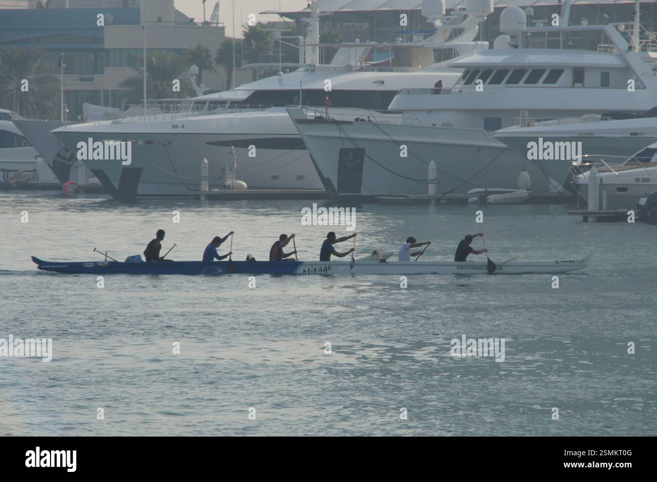 In Dubais geschäftigem Hafen rudert eine Gruppe gemeinsam ein Kanu und demonstriert Teamarbeit und gemeinsame Entschlossenheit für ein gemeinsames Ziel. Alternativ dazu können Sie die verwenden Stockfoto