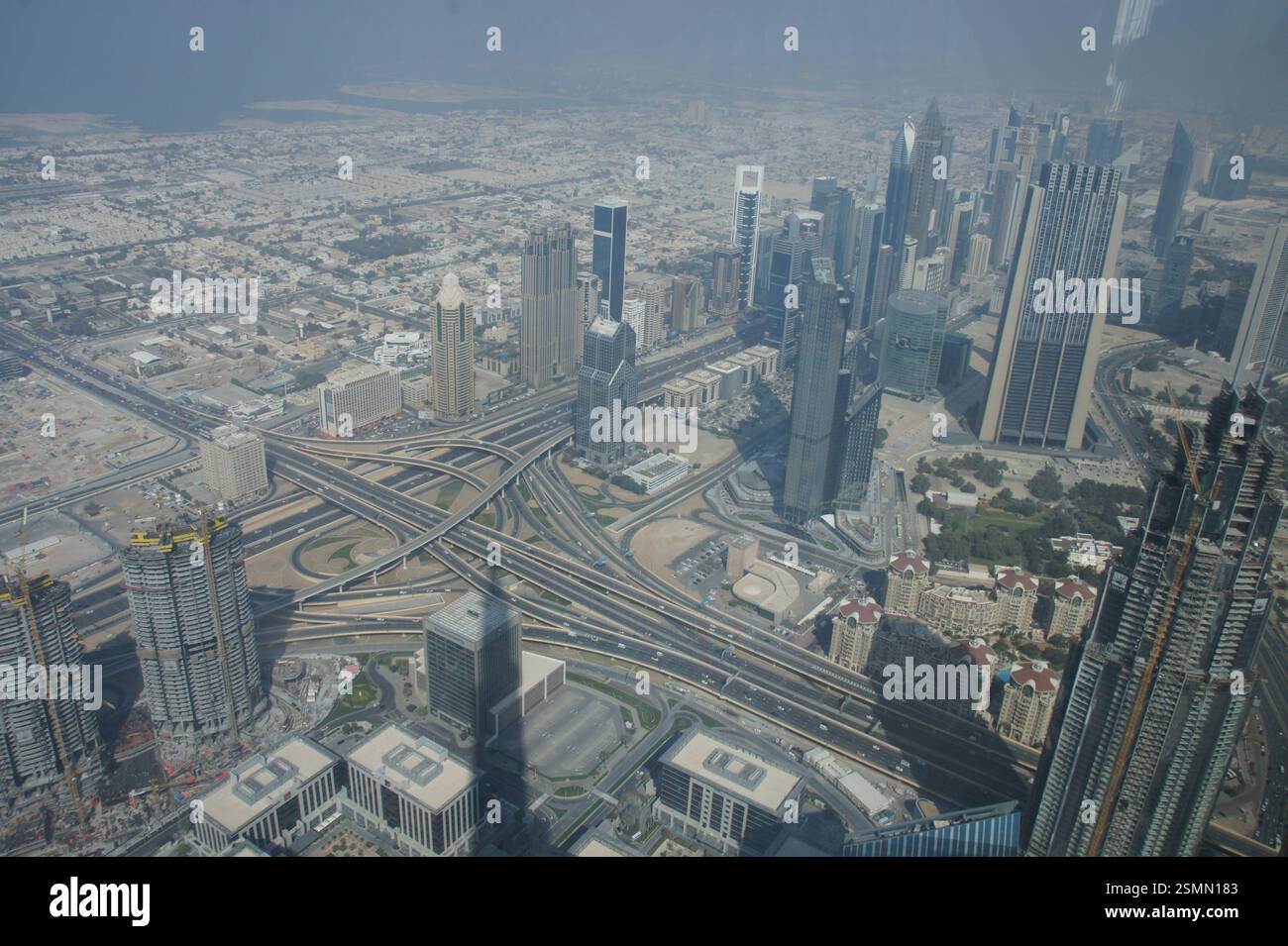 Ein Blick aus der Vogelperspektive auf Dubai offenbart eine geschäftige Kreuzung. Hoch aufragende Wolkenkratzer und Glasriesen bilden den chaotischen Tanz der Fahrzeuge, die in allen hineinströmen Stockfoto