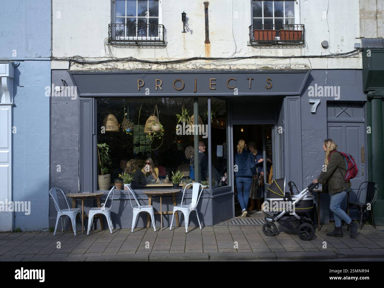 Blick auf ein Café und eine Dame, die einen Kinderwagen schiebt Stockfoto