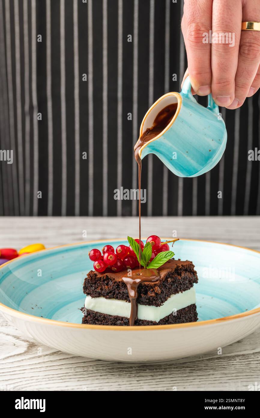 Schokoladenminz-Brownie mit Sahnefüllung, Schokoladensauce und Beeren Stockfoto