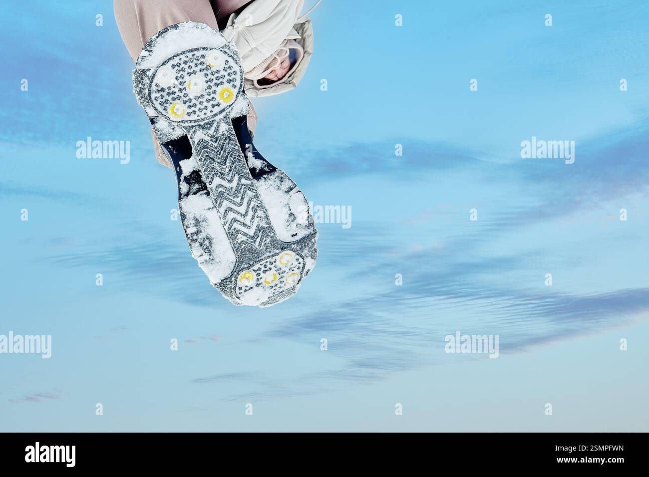 Gummifuß, Metallstollen und gemustertes Profil für besseren Grip auf Eis oder Schnee, niedrige Perspektive auf dem Hintergrund des Himmels. Stockfoto