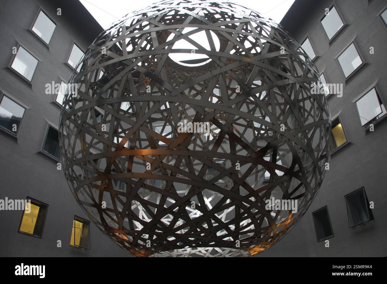 Eine riesige, reflektierende Kugel hängt von der Decke in einem modernen Gebäude in Deutschland, München. Es ist eine schillernde Kunstinstallation, die die Umgebung widerspiegelt. Stockfoto