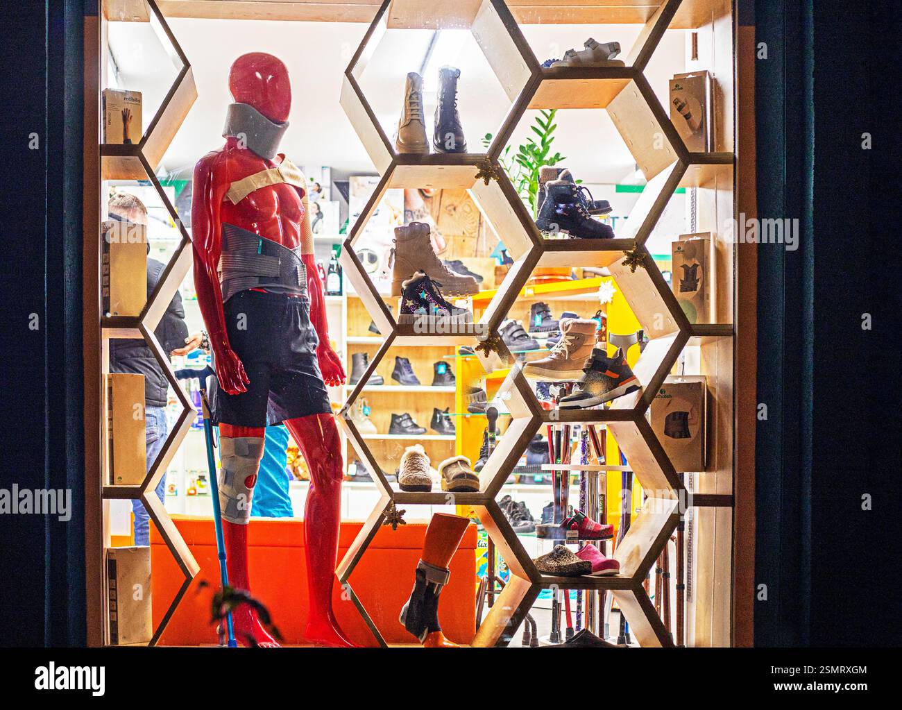 Rote Männerpuppe in Spezialverbänden und Gips vor dem Hintergrund moderner Schuhe Stockfoto