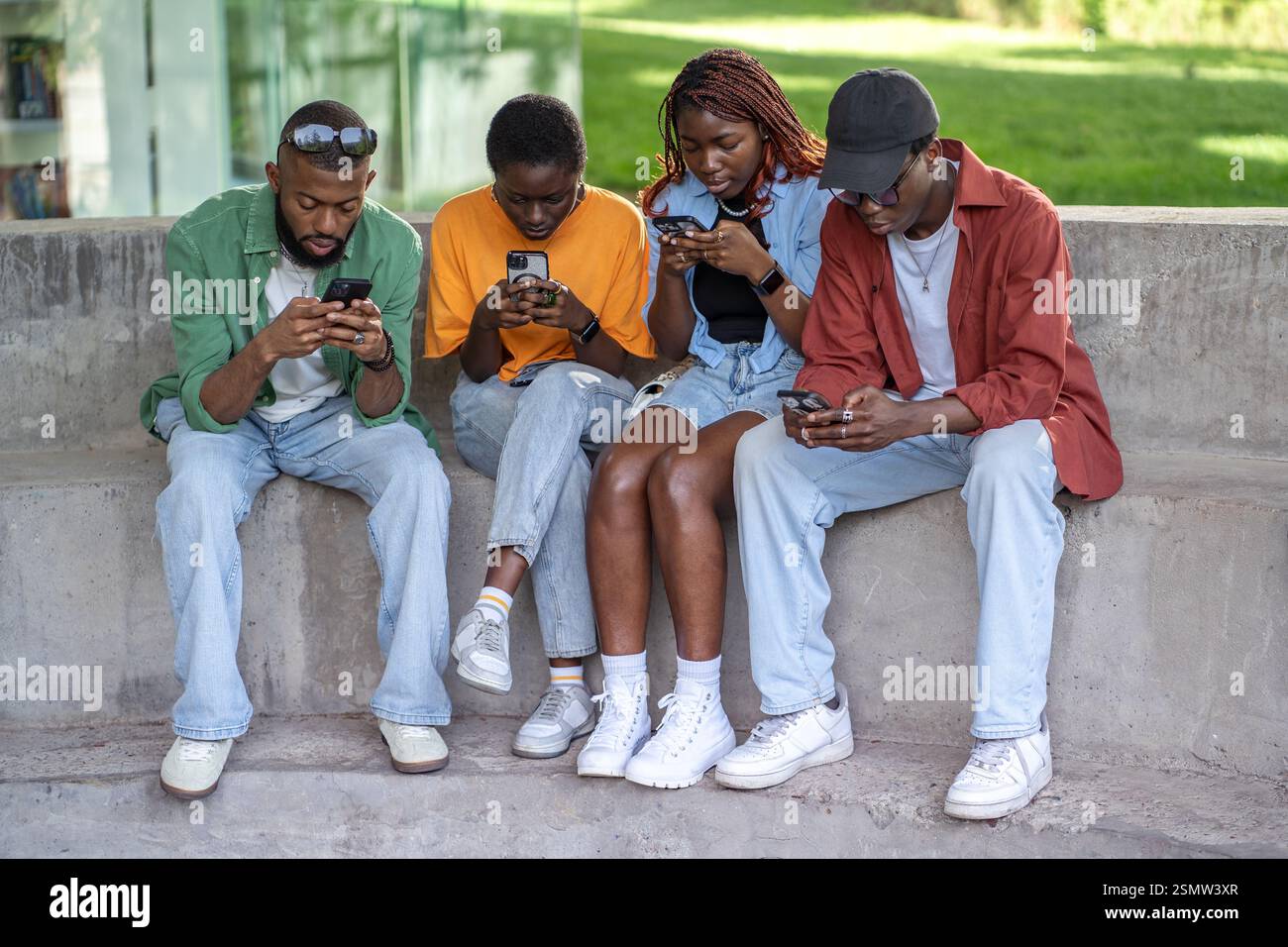 Junge afroamerikanische Jungs klebten an Smartphones, chatten und surfen in sozialen Medien im Park Stockfoto