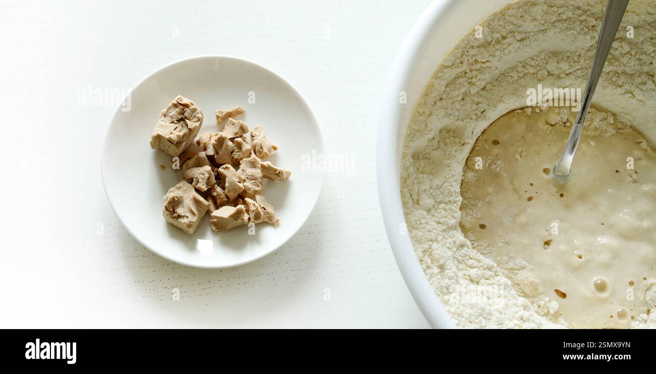 In Mehl gelöste frische Bierhefe für die Zubereitung von Pizzateig, Brot in einer Schüssel und frische Bierhefe auf einem Teller auf weißem Hintergrund. Stockfoto