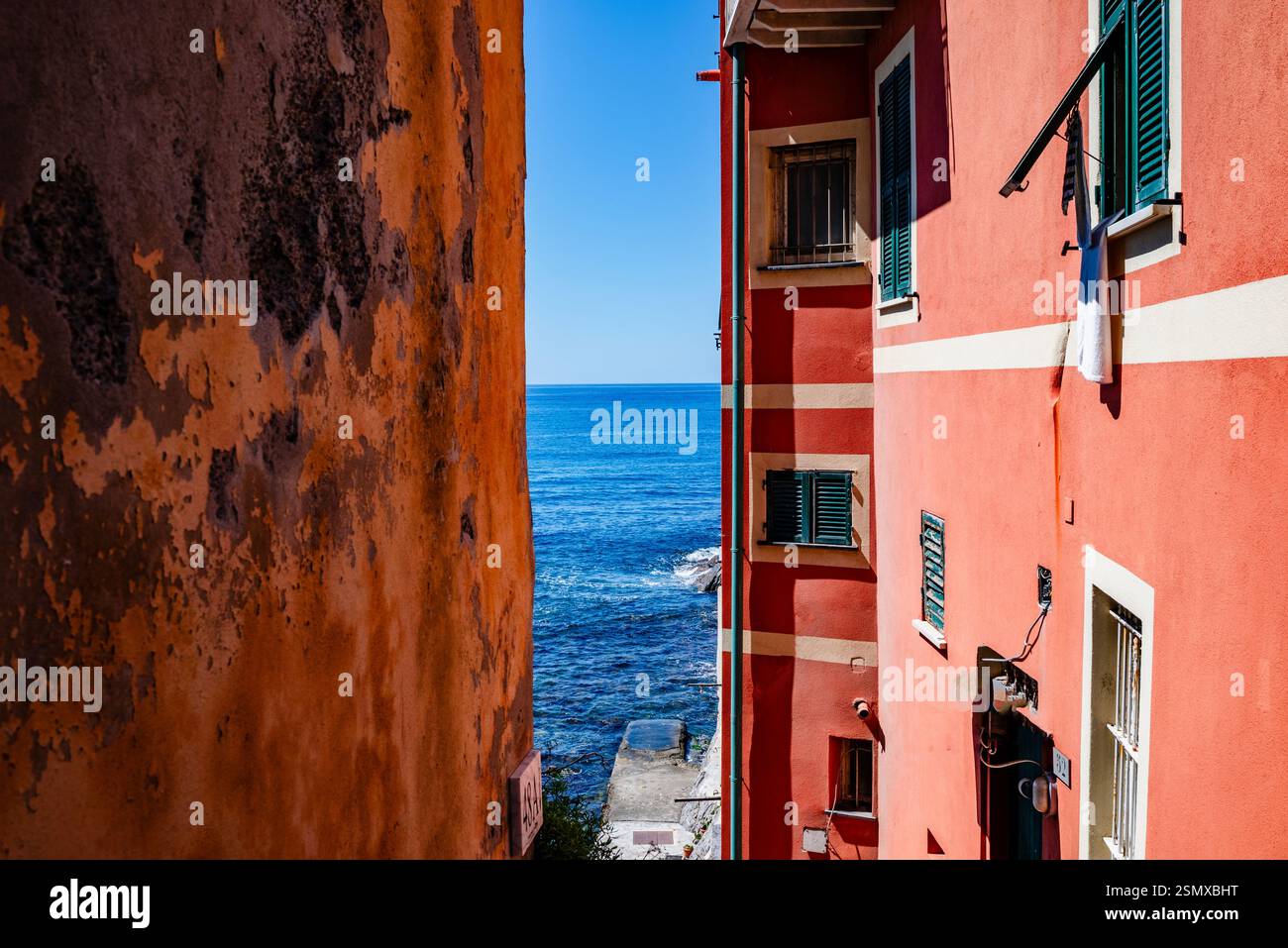 Werfen Sie einen Blick auf das blaue Meer zwischen den hohen bunten Häusern im Fischerdorf Boccadasse, Ligurien, Italien Stockfoto