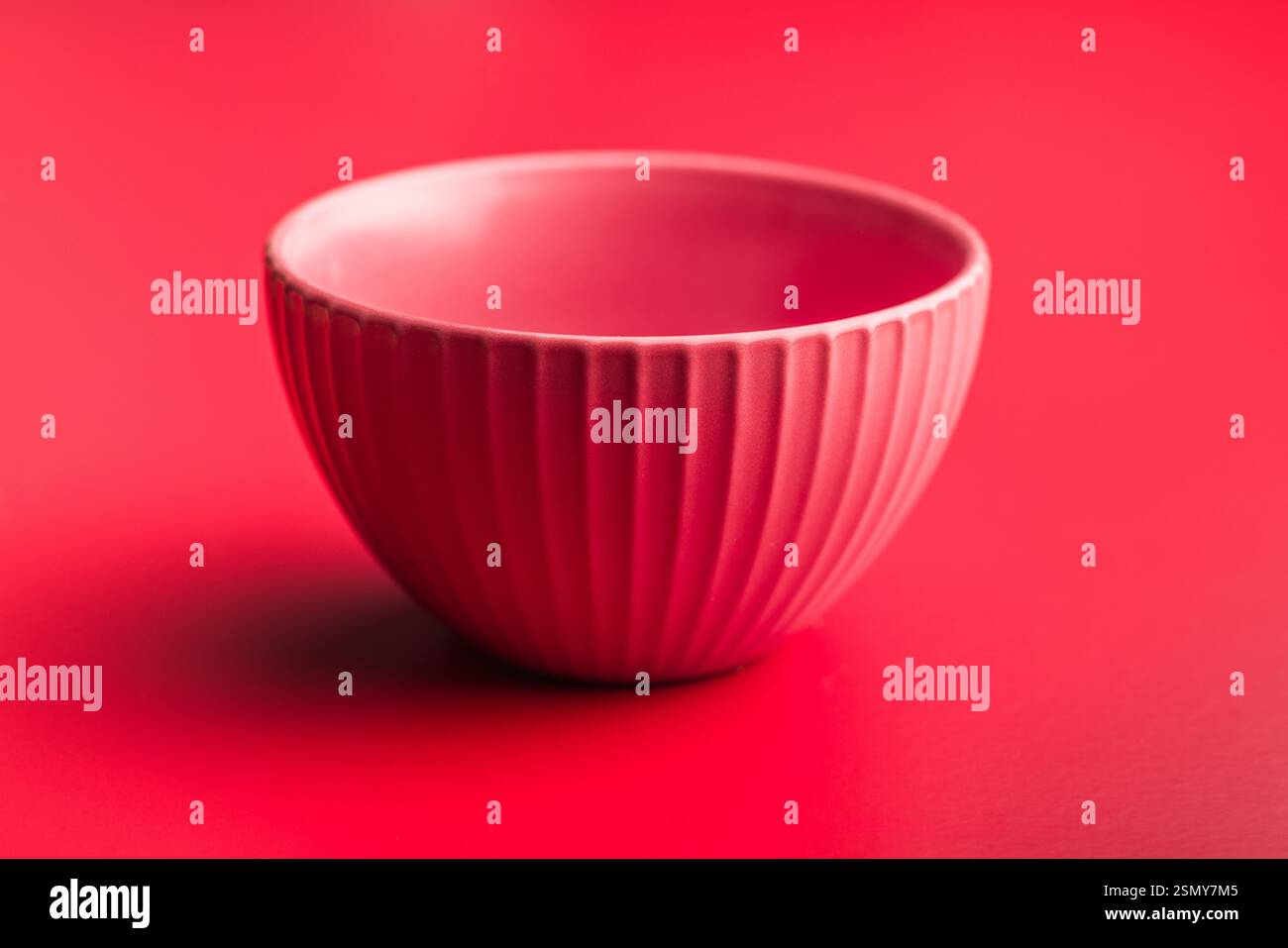 Leere rote Schüssel auf rotem Hintergrund. Stockfoto