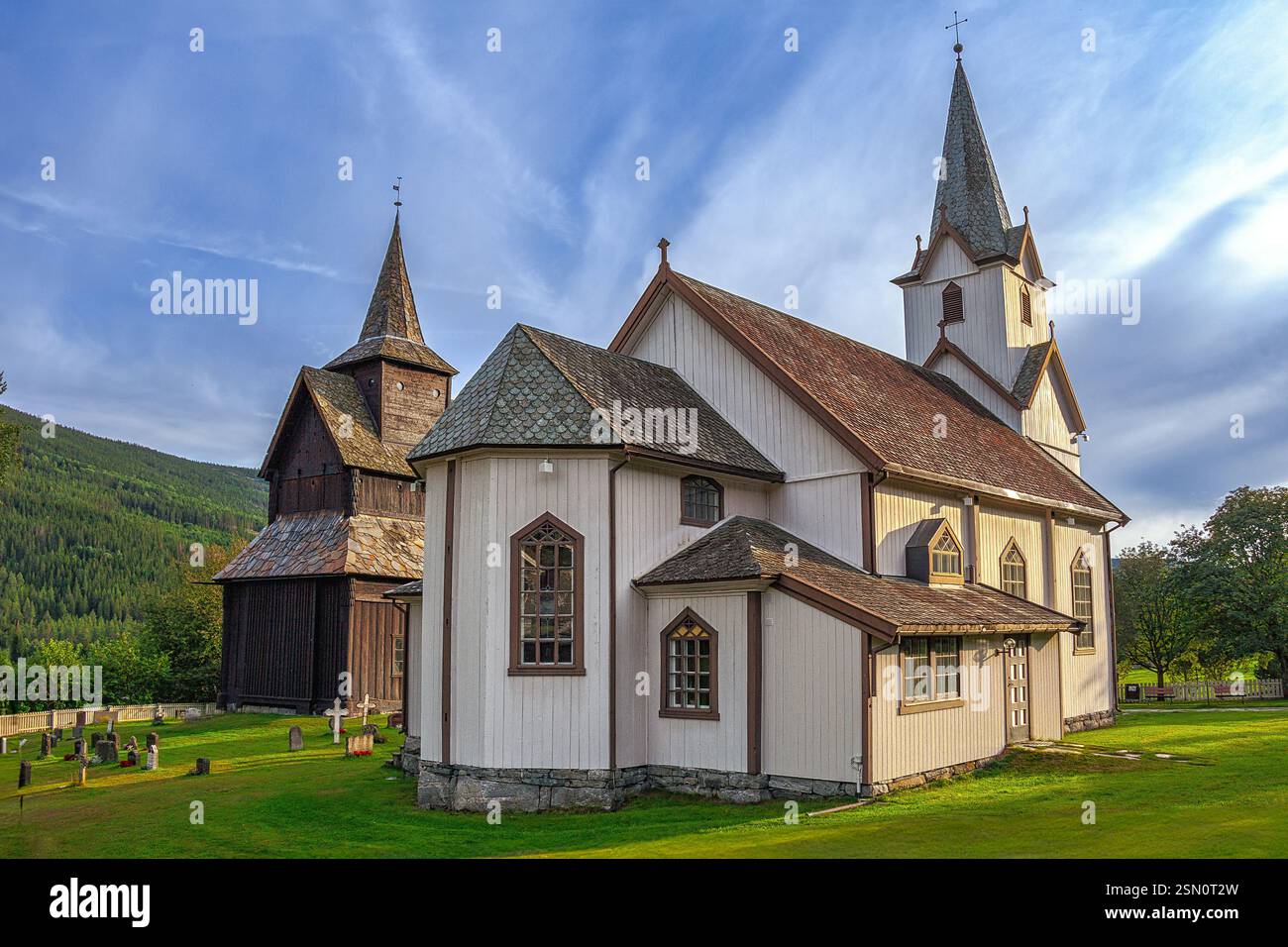 Weiße Holzkirche mit braunem Dach und Glockenturm neben einem alten Holzgebäude mit Friedhof. Torpo, Ål, Buskerud, Norwegen, Europa Stockfoto