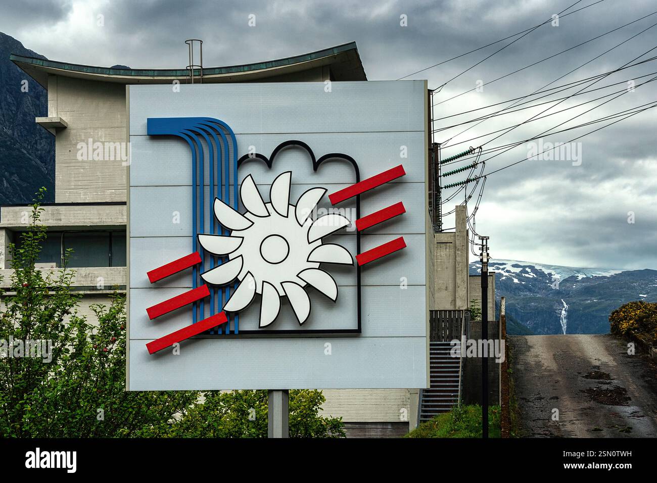 Logo eines Wasserkraftwerks mit rotierender Turbine und Wasserfall des alten Wasserkraftwerks in Odda. Ullensvang, Vestland, Norwegen Stockfoto