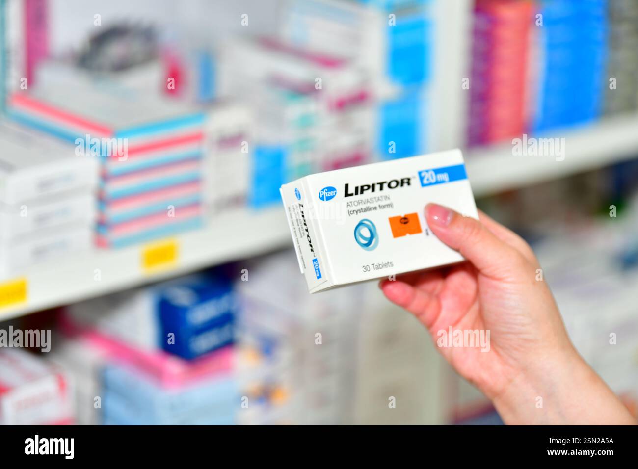 Bangkok, Thailand - 5. März 2022 : Apotheker hält ein Medikament Lipitor 10 mg Box für hohe Blutfettwerte und Packungsbeilage in der Apotheke Drogeriemarkt. Stockfoto