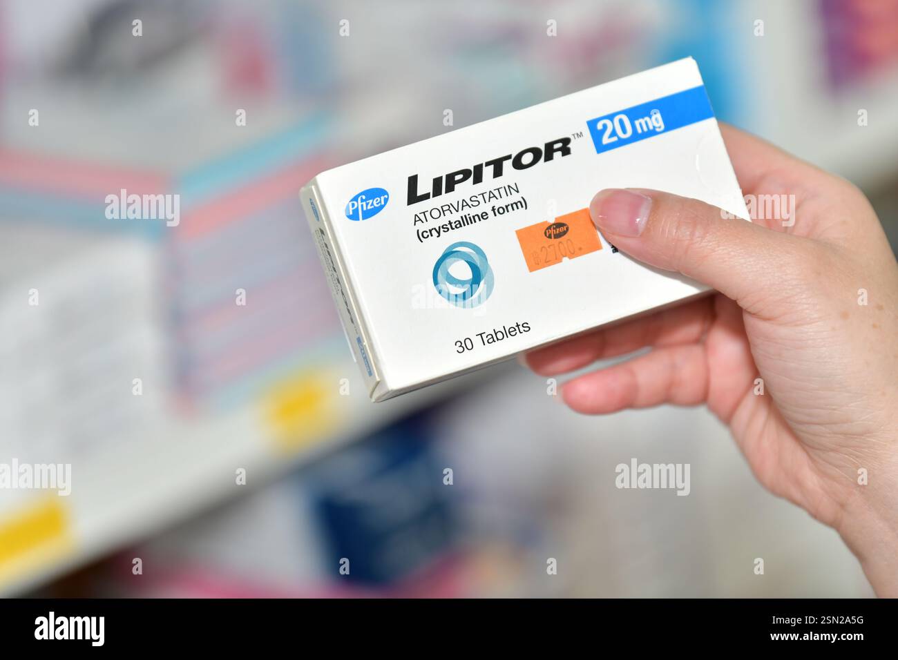 Bangkok, Thailand - 5. März 2022 : Apotheker hält ein Medikament Lipitor 10 mg Box für hohe Blutfettwerte und Packungsbeilage in der Apotheke Drogeriemarkt. Stockfoto