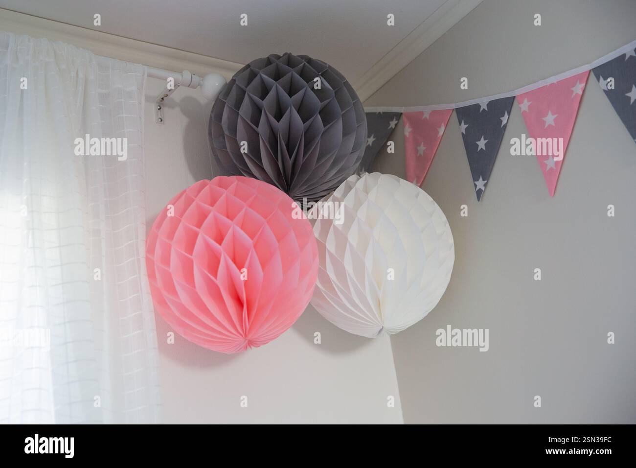 Bunte Papierlaternen an der Wand im Zimmer. Dekoriert mit Fahnen. Bunte Papierlaternen aus Honigkammpapier an der Wand im Zimmer. Stockfoto